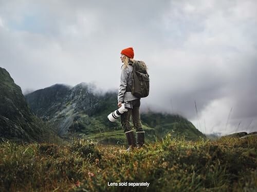 Hiker with camera lens standing in mountainous landscape